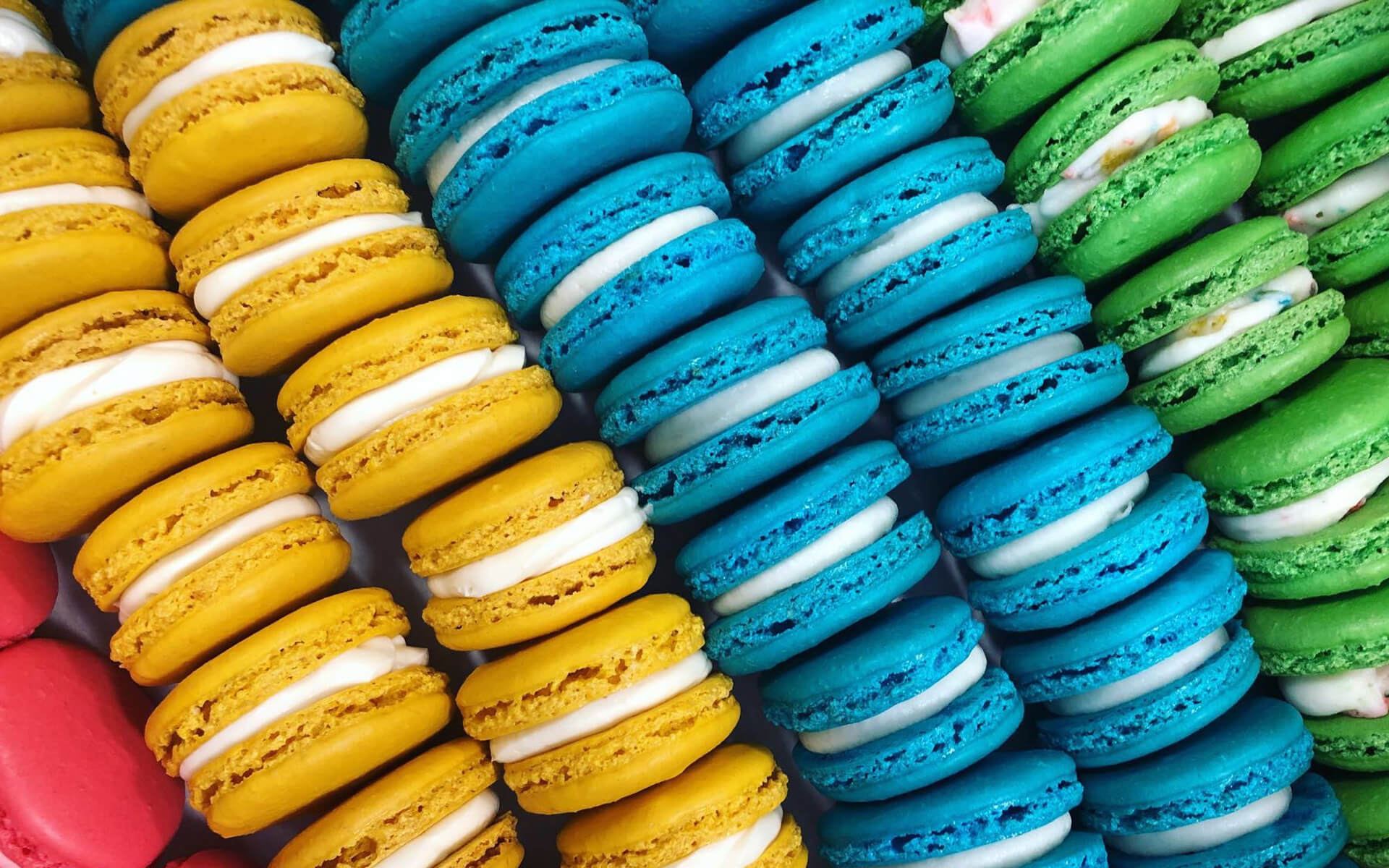 Trays of yellow, blue and green gluten-free macarons