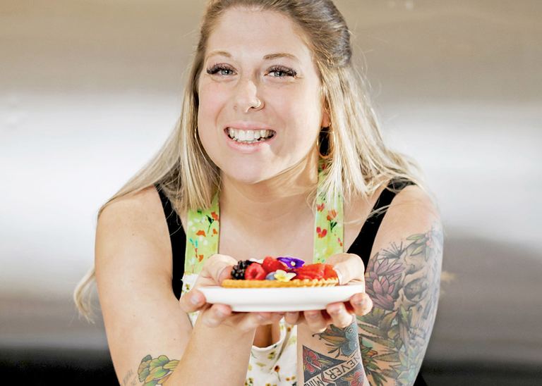 Natalie Schultz holding a plate of decorated desserts in the bakery